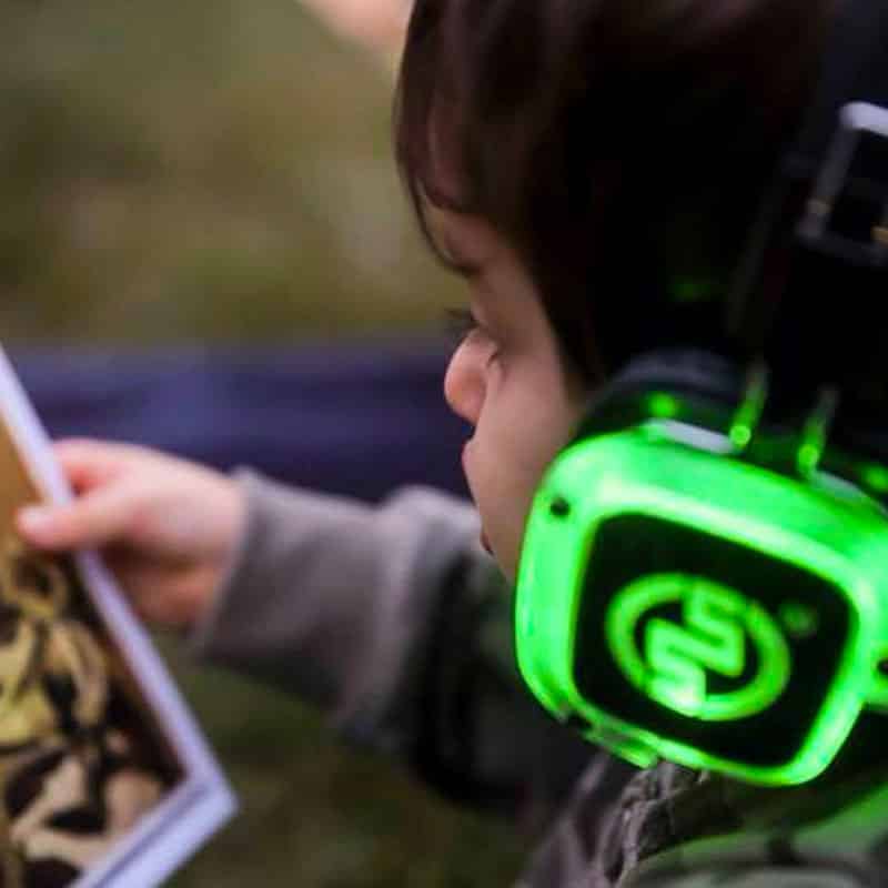silentparty-bambini Boy in green silent disco headphones looking at a postcard