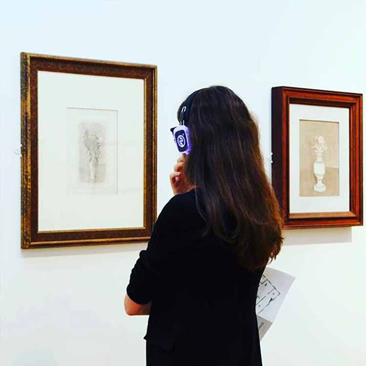 museo-milano Museum visitor in Milan with wireless headphones in front of a painting